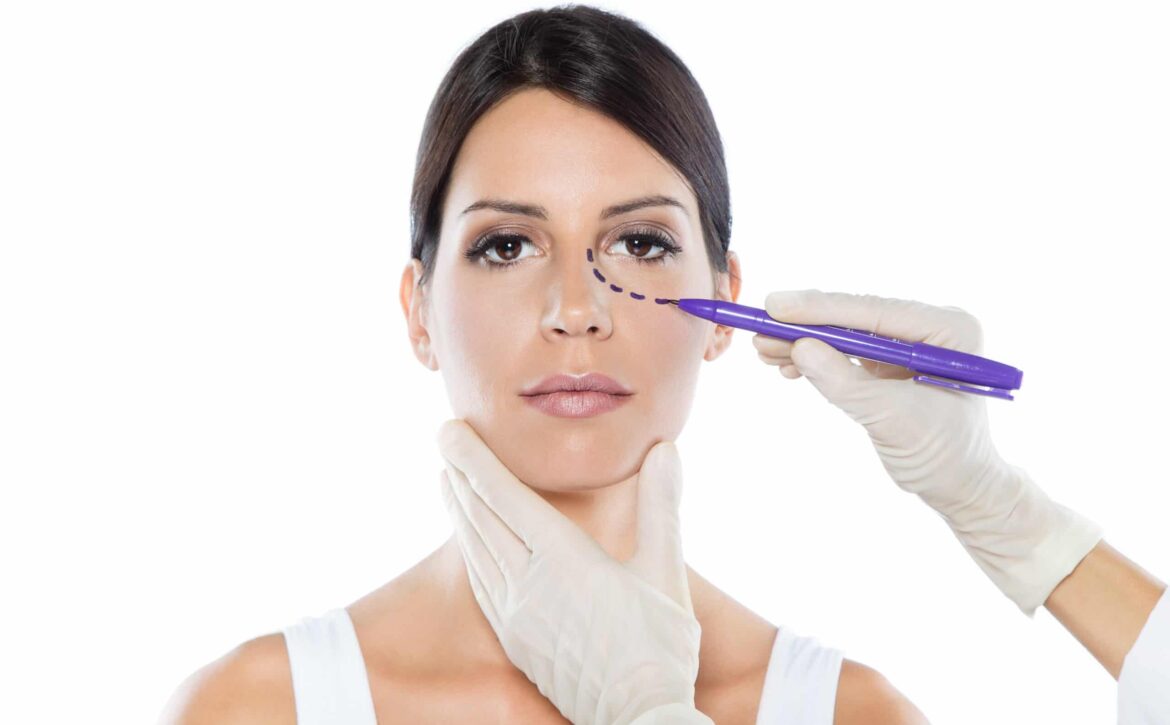 Plastic surgeon drawing dashed lines on her patient's face.